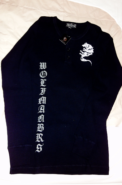 a black woven shirt with a wolf logo and vertical Wolfman brs text